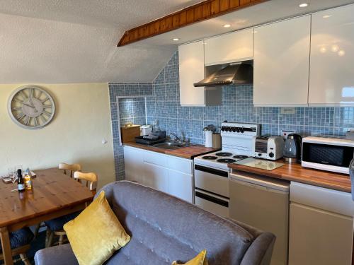 a kitchen with a couch and a table with a clock at The Lookout in Ilfracombe