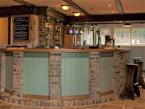 a bar in a restaurant with a stone wall at Duke of Wellington Inn in Corbridge