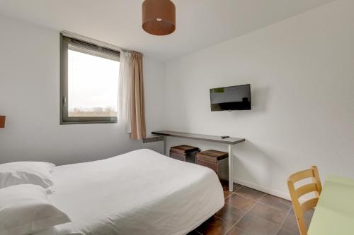 a bedroom with a bed and a desk and a television at All Suites Appart Hôtel - Bordeaux Lac in Bordeaux