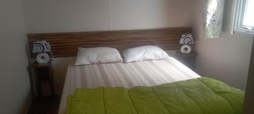 uma cama com um cobertor verde e duas almofadas em Mobil-home Aventura 3 par Catherve em Canet-en-Roussillon