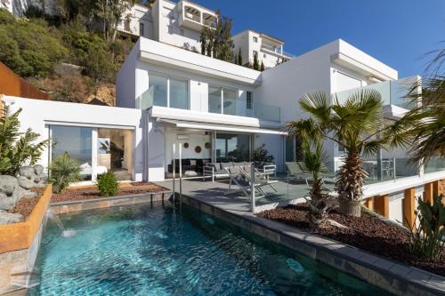une villa avec une piscine en face d'une maison dans l'établissement Vista Roses Mar - Cap Ponent, à Roses