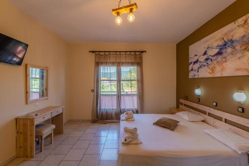 a bedroom with a bed and a desk and a window at Natasa Hotel in Skala Potamias