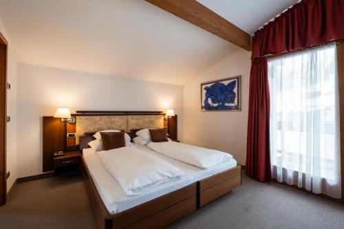 a bedroom with a large bed with a red curtain at Feldmilla Design Hotel - Wellness & SPA in Campo Tures