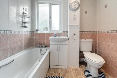 a bathroom with a tub and a toilet and a sink at Dwellers Delight Living Ltd Serviced Accommodation, Chigwell, London 3 bedroom House, Upto 7 Guests, Free Wifi & Parking in London