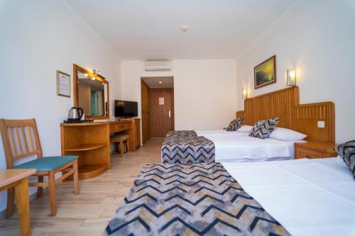 a hotel room with two beds and a desk at Belcehan Hotel in Oludeniz