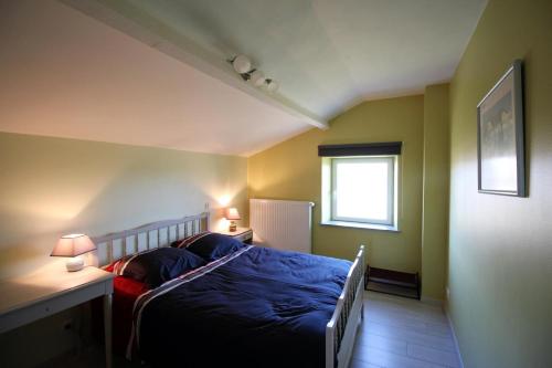 een slaapkamer met een bed met blauwe lakens en een raam bij Chautardie 