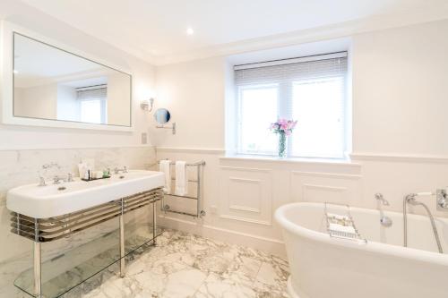 a white bathroom with a tub and a sink at The Grand Hotel in Eastbourne