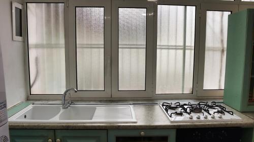 a kitchen with a sink and a stove and windows at La Casa al Porto in Salerno