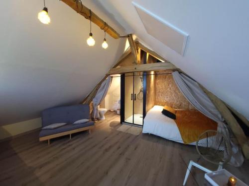 um quarto com uma cama e um sofá no sótão em AU BAIN Normand : bain nordique et détente. em Goderville