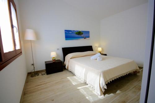 a white bedroom with a bed and two lamps at Villa Franca by Wonderful Italy in San Teodoro