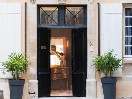 une porte d'entrée d'une maison avec deux plantes en pot dans l'établissement Chez Laurence Du Tilly, à Caen