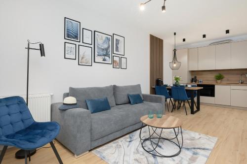 a living room with a gray couch and blue chairs at Wellness & SPA Resort Dziwnów Apartments with Parking by Renters Prestige in Dziwnów