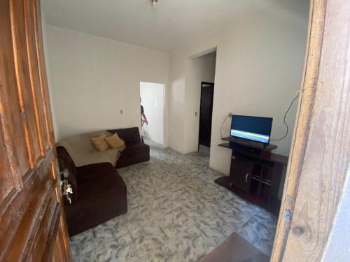 ein Wohnzimmer mit einem Sofa und einem TV in der Unterkunft Apartamento Inteiro Central 2 Quartos e Kitnet Inteira 01 quarto in Ponta Grossa
