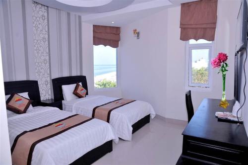 a bedroom with two beds and a desk and a window at Central Ly Son in Ly Son