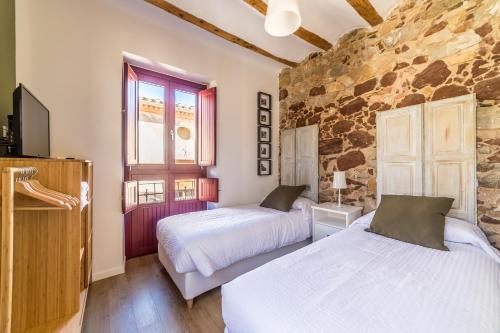 1 dormitorio con 2 camas y pared de piedra en Casa Roja, en Prades