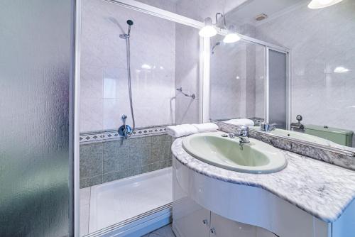 a white bathroom with a sink and a shower at AlohaMundi Plaza de Cuba in Seville