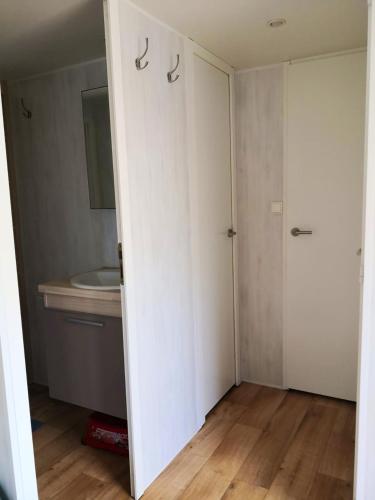 - une porte ouverte donnant sur une salle de bains avec lavabo dans l'établissement Bungalow chaleureux à Saint-Julien-en-Born avec piscine partagée, à Saint-Julien-en-Born