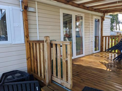 une terrasse couverte à l'avant d'une maison avec une terrasse en bois dans l'établissement Bungalow charmant à Saint-Julien-en-Born avec piscine partagée, à Saint-Julien-en-Born