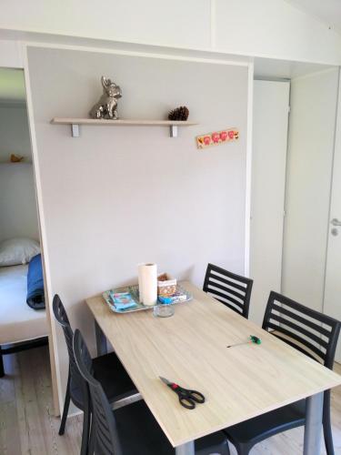 une table avec des chaises et une paire de ciseaux dessus dans l'établissement Bungalow charmant à Saint-Julien-en-Born avec piscine partagée, à Saint-Julien-en-Born
