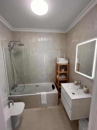 e bagno con vasca, servizi igienici e lavandino. di Costa de Caparica a Costa da Caparica