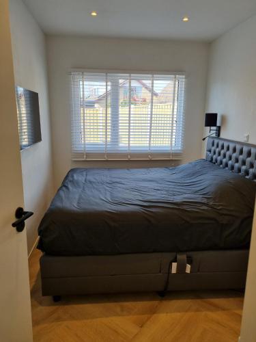 a bedroom with a bed and a large window at Calm Down Near The Sea in Vlissingen