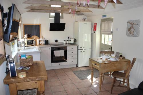 eine Küche mit weißen Geräten und einem Tisch darin in der Unterkunft Dairy Cottage Luxury B&B in Attleborough