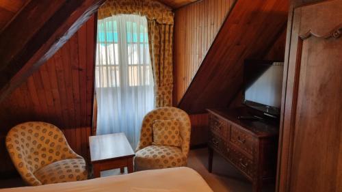 a hotel room with two chairs and a television at Hotel de la Poste in Corps