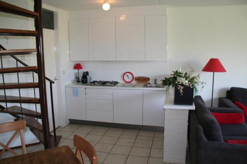 cocina con armarios blancos y sala de estar. en Liguster 8 en Nieuwvliet