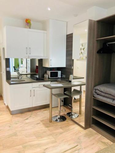 une cuisine avec des armoires blanches et une table et des chaises dans l'établissement Studio de luxe Miramar, à Cannes