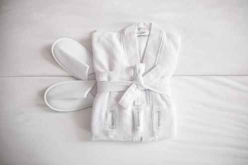 a white robe with a bow and a pair of shoes at Hotel Navarra Brugge in Bruges
