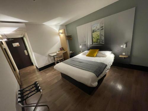 een slaapkamer met een groot bed met een geel kussen bij B&B HOTEL Chaumont in Chaumont