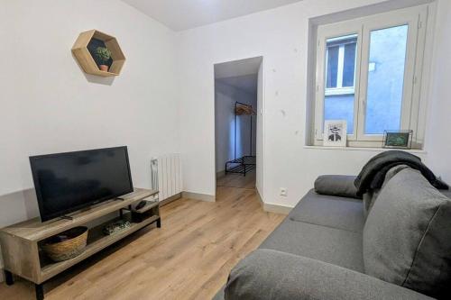 sala de estar con sofá y TV de pantalla plana en Zen Home - appartement jusqu'à 4 voyageurs, en Nantua