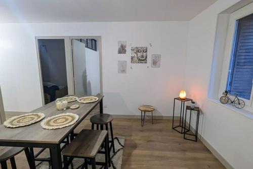 una sala da pranzo con tavolo e sedie in legno di Zen Home - appartement jusqu'à 4 voyageurs a Nantua