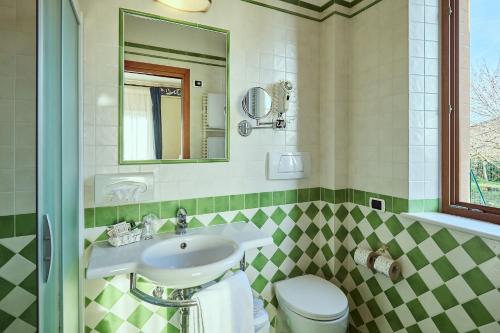bagno con lavandino, servizi igienici e specchio di Piccolo Hotel La Valle a Pienza