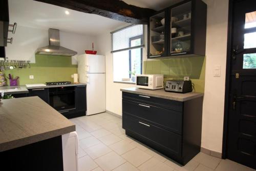 uma cozinha com armários pretos e um frigorífico branco em Les moissonneurs em Champagnac-la-Rivière