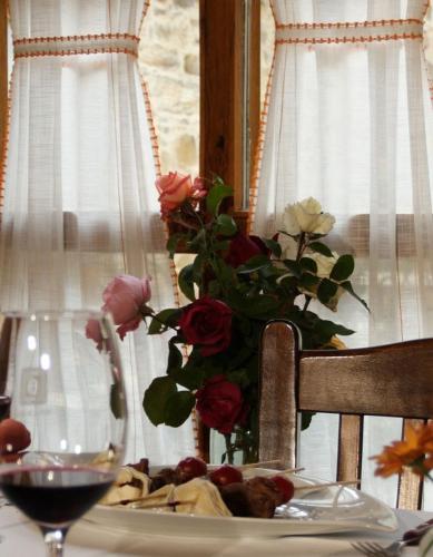 a table with a plate of roses and a vase of flowers at Casa Pepa Hotel Rural in Santa Colomba de Somoza