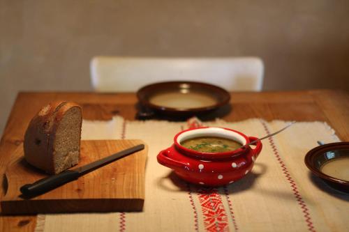 a wooden table with a red bowl of soup and a knife at Holiday Home Trnavsko in Bogojina
