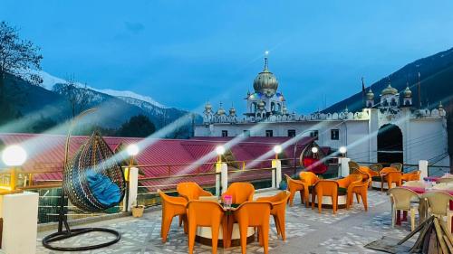 a patio with tables and chairs and a building at Hotel Hilltop At Mall Road Manali With Open Terrace in Manāli