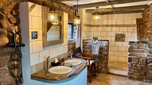 a bathroom with two sinks and a stone wall at Namib Outpost in Sesriem
