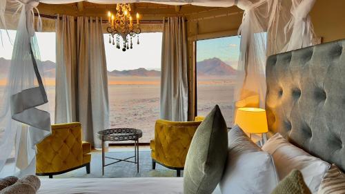 a bedroom with a bed with a view of the desert at Namib Outpost in Sesriem