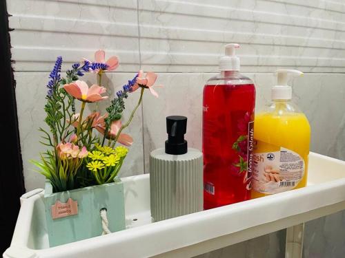 a shelf with two bottles of soap and flowers at Luxury private Studio apartment close to Airport in Abu Dhabi
