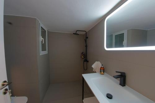 a bathroom with a sink and a shower with a window at Esperidon Luxury Apartment Glyfada in Athens