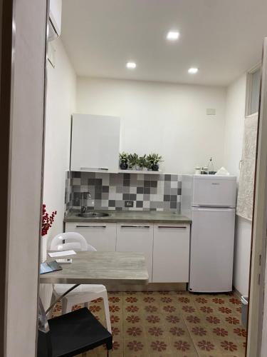 - une cuisine avec des placards blancs, une table et un réfrigérateur dans l'établissement Marta House 2, à Trapani