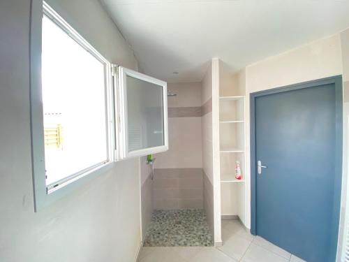 La salle de bains est pourvue d'une grande fenêtre et d'une porte bleue. dans l'établissement Chambre douillette, calme, lit queen size wifi, à Avrillé