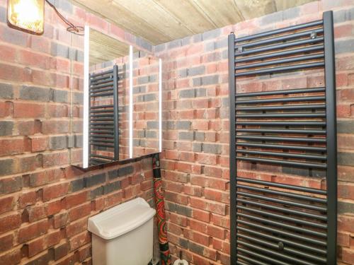 een badkamer met een bakstenen muur en een toilet bij Compton Lodge in Buxton