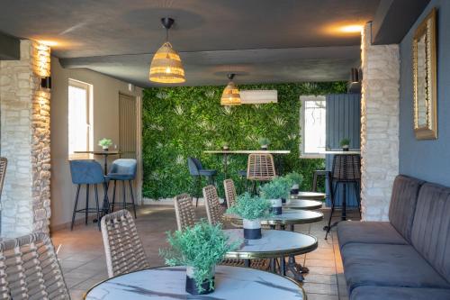 a patio with tables and chairs and a green wall at Hôtel La Perna in Pernes-les-Fontaines