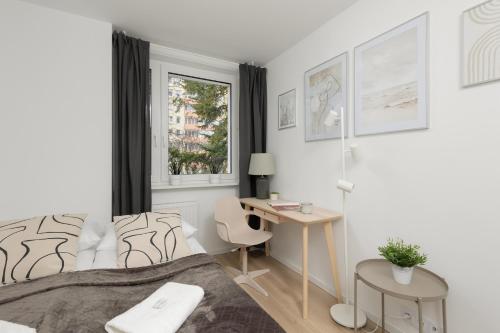 a bedroom with a bed and a desk and a window at Metro Bemowo Apartment by Renters in Warsaw