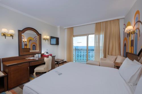 a hotel room with a bed and a desk and a bedroom at Megasaray Westbeach Antalya in Antalya