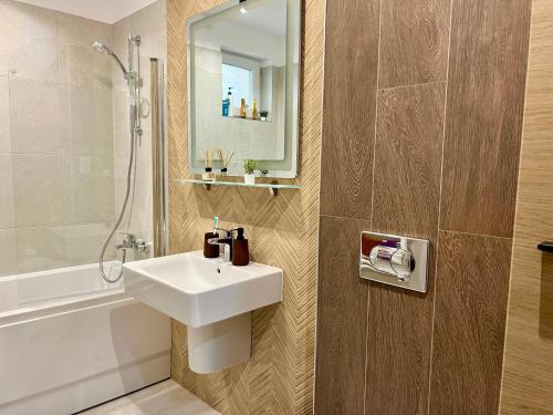 ein Badezimmer mit einem weißen Waschbecken und einer Dusche in der Unterkunft Mountain Retreat-Modern 1BR w/ Fireplace & Parking in Braşov