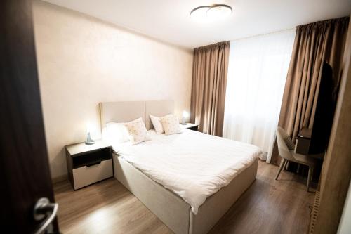 ein Schlafzimmer mit einem Bett mit weißen Laken und Kissen in der Unterkunft Mountain Retreat-Modern 1BR w/ Fireplace & Parking in Braşov